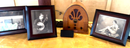 A vintage cathedral-style radio flanked by two framed period portraits