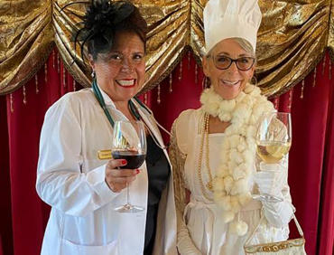 Two guests in costume, the winners of the Murder Mystery game, celebrating with raised glasses